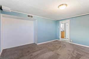 Empty room with carpet floors, a textured ceiling, and crown molding