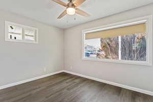 Unfurnished room featuring ceiling fan and dark wood-type flooring