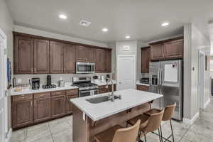 Kitchen with appliances with stainless steel finishes, sink, a kitchen breakfast bar, a kitchen island with sink, and light tile patterned floors