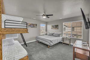 Bedroom with ceiling fan, a textured ceiling, and carpet