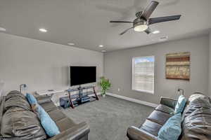 Living room with ceiling fan, light colored carpet, and a textured ceiling