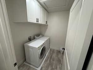 Clothes washing area with cabinets, washing machine and dryer, and light hardwood / wood-style floors