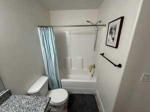 Full bathroom featuring tile patterned floors, toilet, vanity, and shower / tub combo with curtain