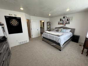 Carpeted bedroom featuring a textured ceiling and ensuite bathroom