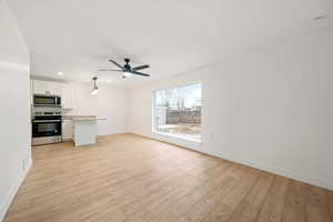 Unfurnished living room featuring ceiling fan and light hardwood / wood-style flooring