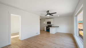 Interior space with white cabinets, ceiling fan, light hardwood / wood-style floors, and appliances with stainless steel finishes