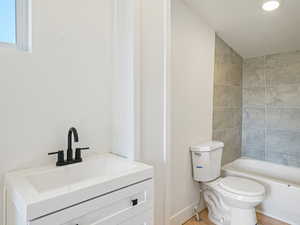 Full bathroom with tiled shower / bath combo, toilet, and vanity