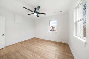 Empty room featuring ceiling fan, light hardwood / wood-style floors, and a wealth of natural light