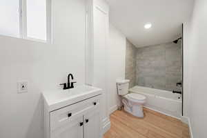 Full bathroom with hardwood / wood-style flooring, toilet, vanity, and tiled shower / bath