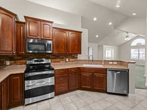 Kitchen with sink, tasteful backsplash, vaulted ceiling, and appliances with stainless steel finishes