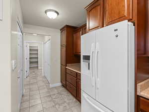 Kitchen featuring white refrigerator with ice dispenser and a textured ceiling