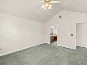 Interior space with ceiling fan, connected bathroom, lofted ceiling, and carpet flooring