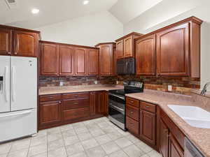 Kitchen with decorative backsplash, sink, appliances with stainless steel finishes, and light tile patterned flooring