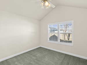 Carpeted empty room with vaulted ceiling and ceiling fan