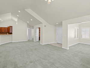 Unfurnished living room with light carpet, ceiling fan, and lofted ceiling