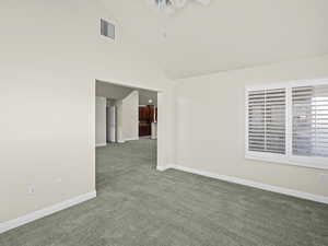 Carpeted empty room featuring ceiling fan and high vaulted ceiling