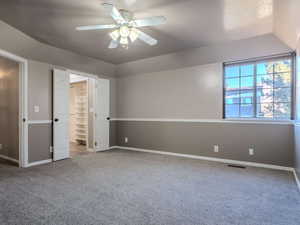 Unfurnished bedroom featuring lofted ceiling, carpet, a spacious closet, ceiling fan, and a closet