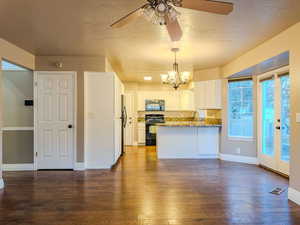 Kitchen with white cabinetry, range with electric stovetop, kitchen peninsula, stone counters, and pendant lighting