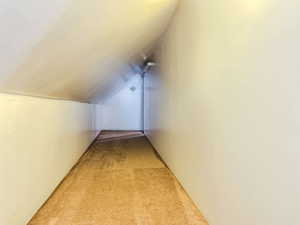 Hallway featuring light carpet and vaulted ceiling