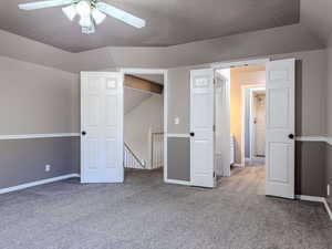 Unfurnished bedroom with lofted ceiling, a textured ceiling, light colored carpet, and ceiling fan