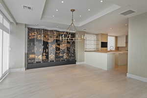 Unfurnished dining area featuring light hardwood / wood-style flooring and a raised ceiling