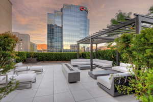 Patio terrace at dusk with a pergola and an outdoor living space with a fire pit