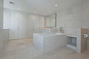 Bathroom featuring vanity, tile walls, and a relaxing tiled tub