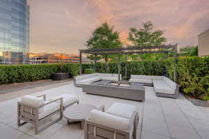 Patio terrace at dusk with an outdoor living space with a fire pit and a pergola