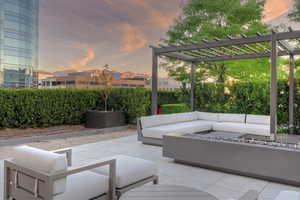 Patio terrace at dusk with an outdoor hangout area and a pergola