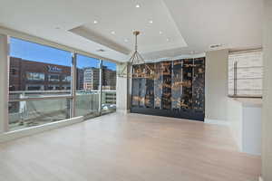 Unfurnished room featuring hardwood / wood-style flooring, a raised ceiling, and floor to ceiling windows