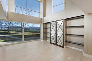 Interior space with built in shelves, hardwood / wood-style floors, plenty of natural light, and a high ceiling