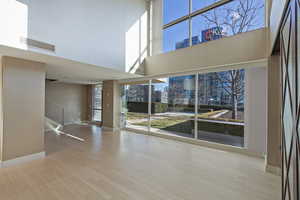 Empty room featuring light wood-type flooring and a high ceiling