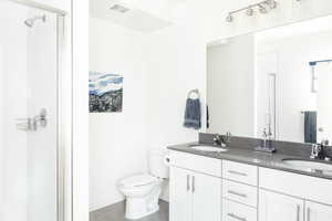 Bathroom featuring toilet, vanity, and an enclosed shower