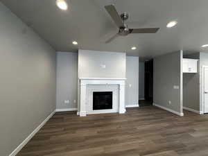 Unfurnished living room with ceiling fan, dark hardwood / wood-style floors, and a fireplace