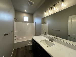 Full bathroom with hardwood / wood-style flooring, toilet, vanity, and bathing tub / shower combination