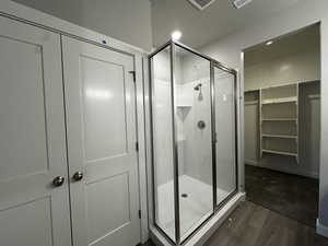 Bathroom featuring a shower with shower door and wood-type flooring