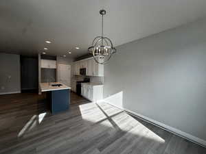 Kitchen with sink, a kitchen island with sink, range with electric stovetop, and white cabinetry