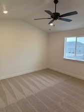 Unfurnished room featuring ceiling fan, carpet, and lofted ceiling