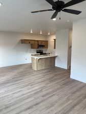 Kitchen featuring ceiling fan, light hardwood / wood-style flooring, appliances with stainless steel finishes, and a kitchen breakfast bar