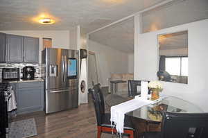 Dining room featuring vaulted ceiling, dark hardwood / wood-style floors, and a textured ceiling