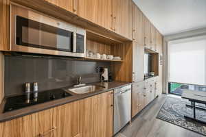 Kitchen with dark wood-type flooring, appliances with stainless steel finishes, and sink