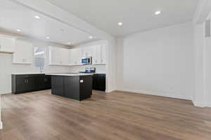 Kitchen with white cabinets, a center island, light hardwood / wood-style floors, and appliances with stainless steel finishes