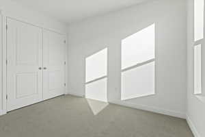 Unfurnished bedroom featuring a closet and light carpet