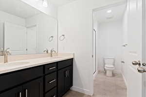 Bathroom featuring toilet, a shower with shower door, tile patterned floors, and vanity