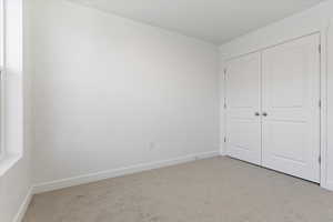 Unfurnished bedroom with a closet and light carpet