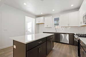 Kitchen featuring sink, white cabinets, dark hardwood / wood-style floors, a kitchen island, and stainless steel appliances