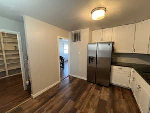 Kitchen with stainless steel refrigerator with ice dispenser, white cabinetry, and dark hardwood / wood-style floors