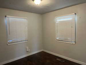 Empty room featuring dark hardwood / wood-style flooring