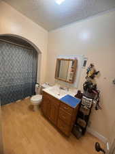 Bathroom featuring a textured ceiling, toilet, vanity, and hardwood / wood-style floors