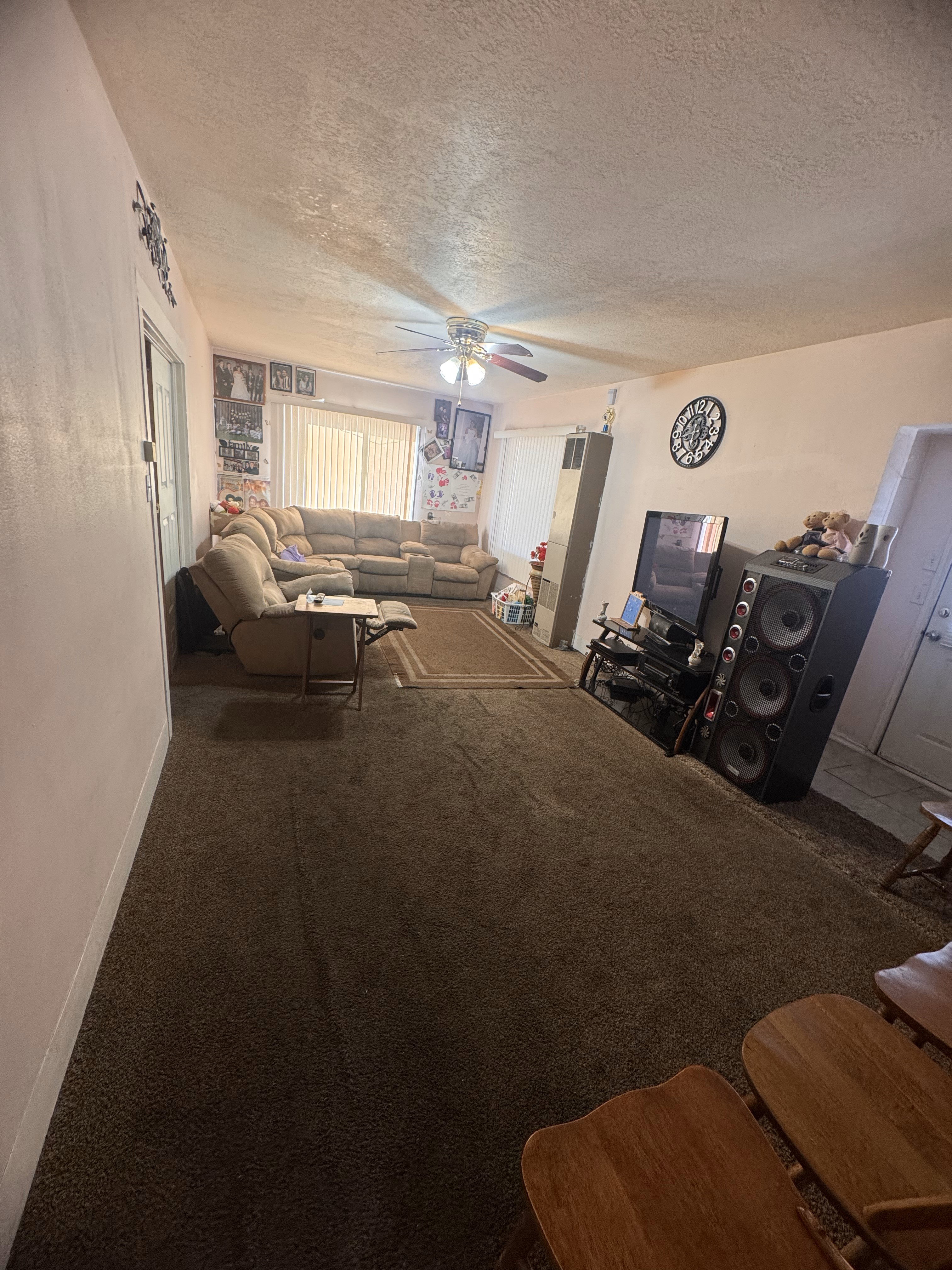 Living room with ceiling fan, a textured ceiling, and carpet